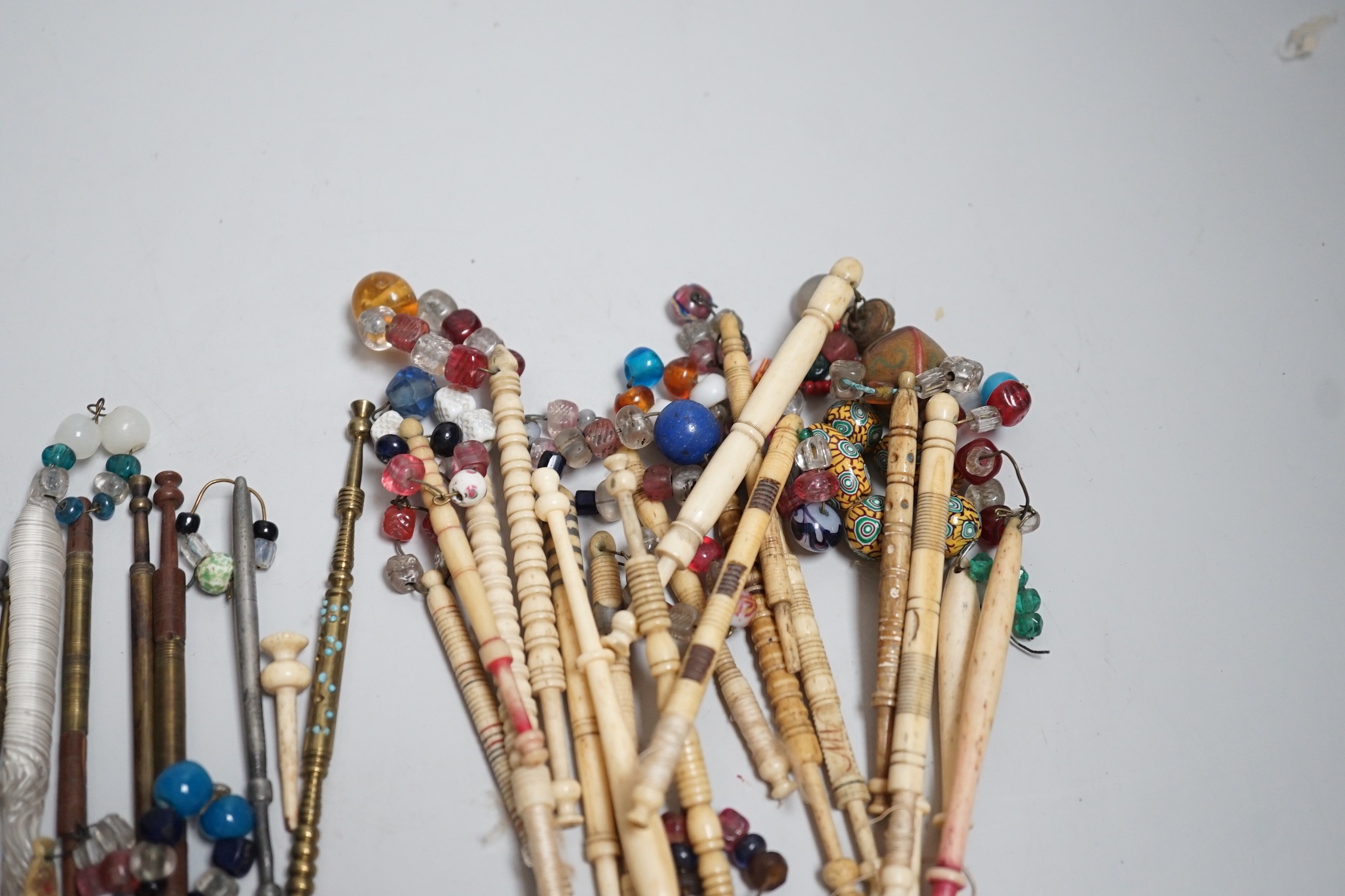 Twenty ornate 19th century turned bone and beaded topped lace bobbins and eleven ornately turned metal lace bobbins, glass bobbin and 3 broken bobbins (34)